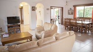 A spacious living room with a leather sofa, wooden coffee table, and a TV. There is a dining area with a table and chairs. - Villa Marina for rent in Kathikas,Paphos ..Family friendly near Coral Bay. (Paphos)