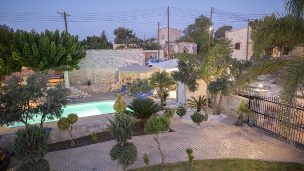 A pool area with a stone wall, palm trees, and a paved walkway. - Villa Marina for rent in Kathikas,Paphos ..Family friendly near Coral Bay. (Paphos)