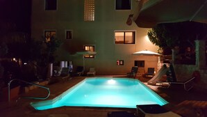 A swimming pool with a slide, surrounded by lounge chairs and umbrellas, in a courtyard with a building in the background. - Villa Marina for rent in Kathikas,Paphos ..Family friendly near Coral Bay. (Paphos)