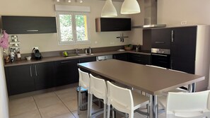 Une cuisine moderne dotée d’un îlot central, de chaises blanches et d’appareils électroménagers en acier inoxydable.