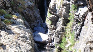 Un cañón estrecho con un arroyo cristalino y una cascada.