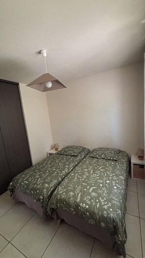 Un dormitorio con una cama, una mesita de noche, una lámpara y una lámpara de techo.