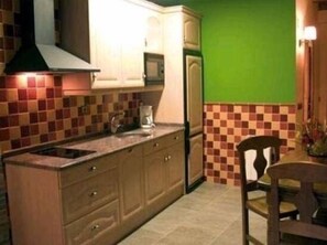 Modern kitchen with central island, sink, and stovetop, flanked by cabinets and a green wall.