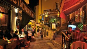 Una calle estrecha con mesas al aire libre en distintos establecimientos, incluyendo un restaurante llamado Gavroche.
