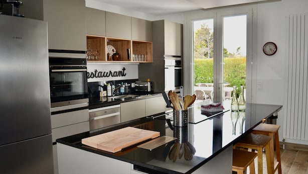 A modern kitchen with a central island, stainless steel appliances, and a view to the outdoors. - House with terraces and unobstructed view of the beach with direct access (Saint-Aubin-Sur-Mer)