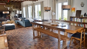 A spacious living area with a wooden dining table, benches, and a blue sofa. - House with terraces and unobstructed view of the beach with direct access (Saint-Aubin-Sur-Mer)