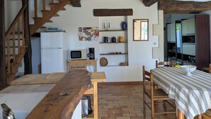 Eine rustikale Küche mit einer Holztreppe, einem weißen Kühlschrank, einer Mikrowelle und einer Kaffeemaschine auf einem Holztisch.