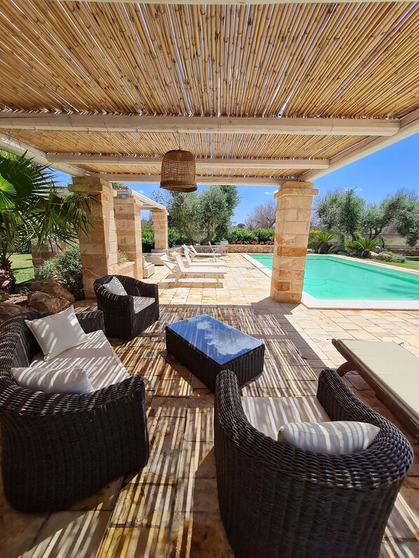 Une terrasse extérieure avec des meubles en osier, une piscine et un plafond en bambou.