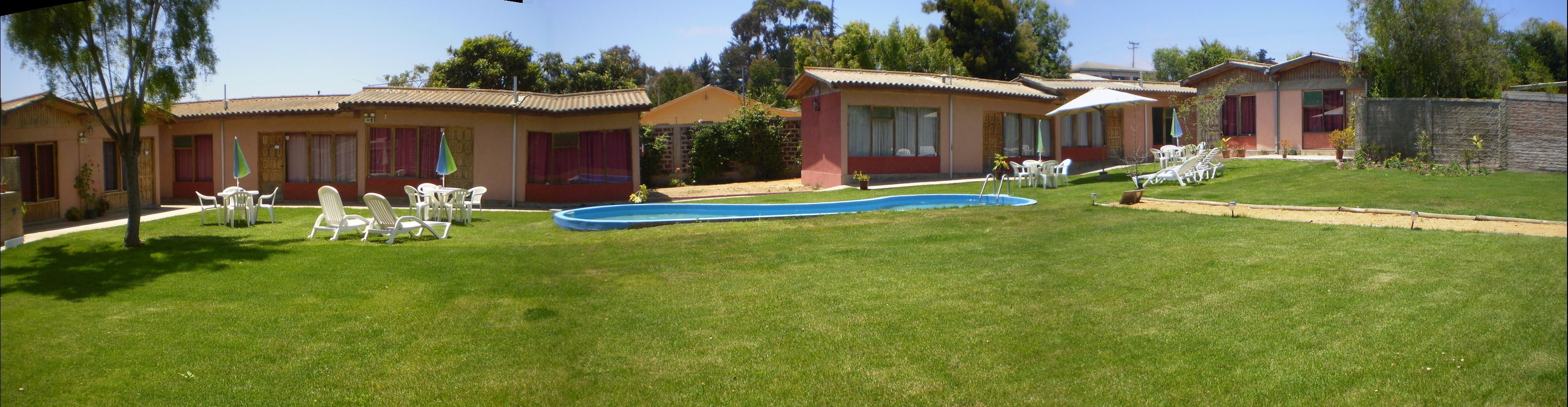 Zona residencial con varias casas, piscina y mobiliario de exterior.