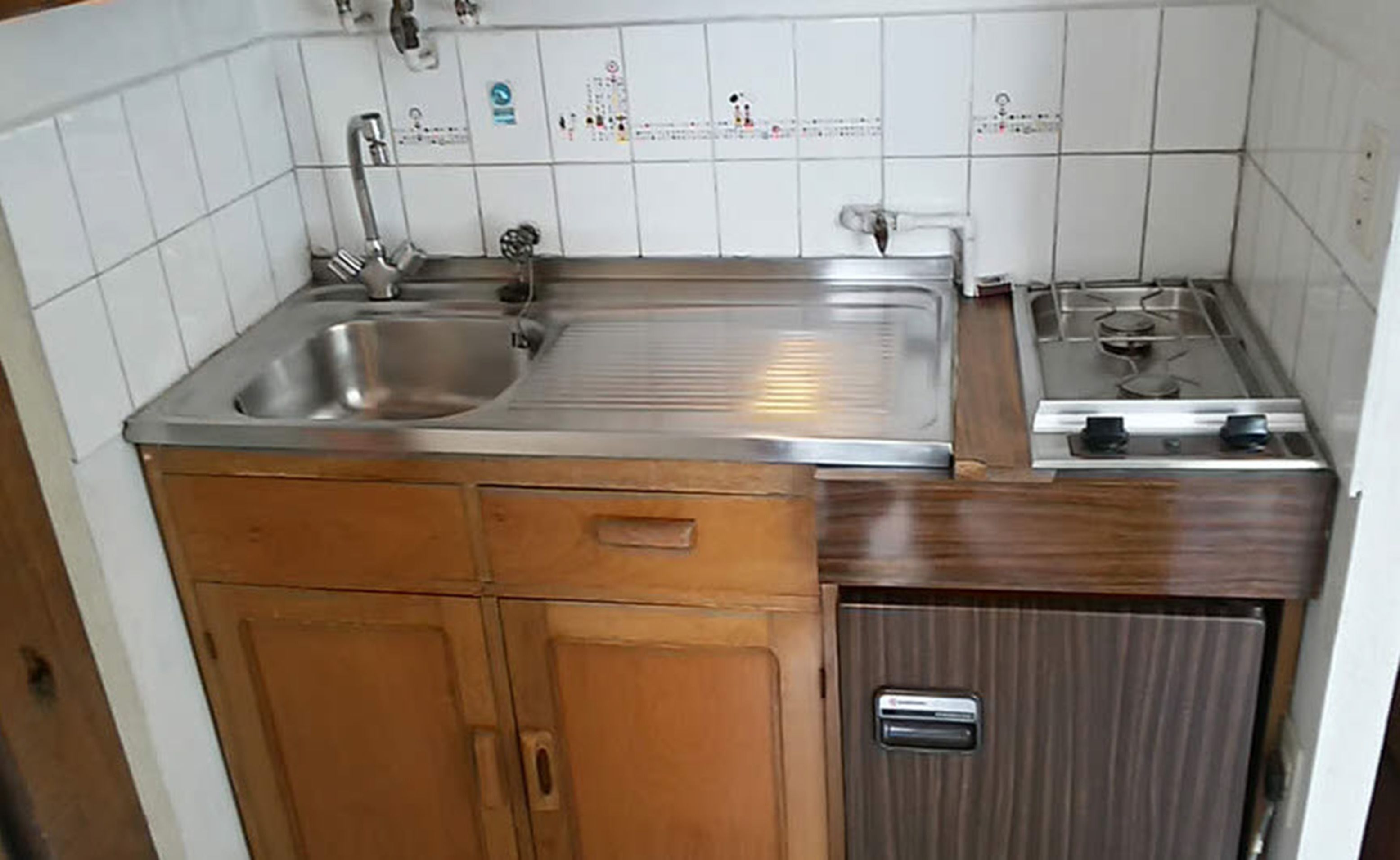 A kitchen with a stainless steel sink, wooden cabinets, and a built-in stove.