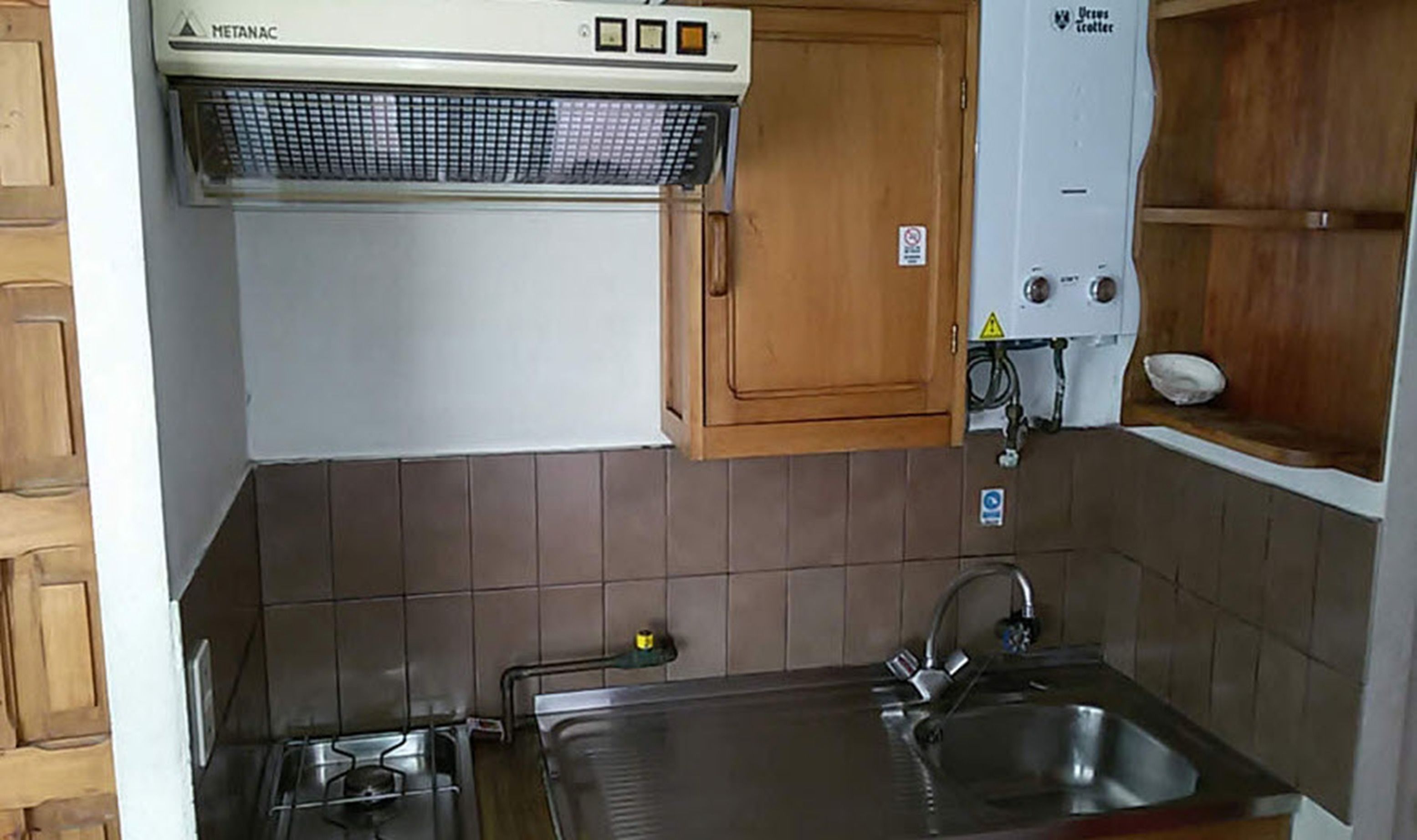 Een kleine keuken met een gasfornuis, een spoelbak en een ingebouwde oven.