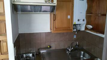 Een kleine keuken met een gasfornuis, een spoelbak en een ingebouwde oven.