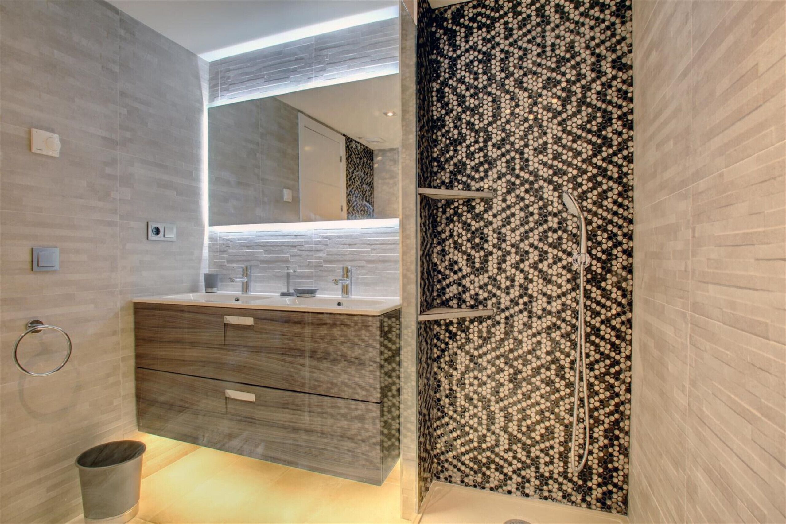 Een moderne badkamer met een wastafel, een douche en een wand met een patroon.