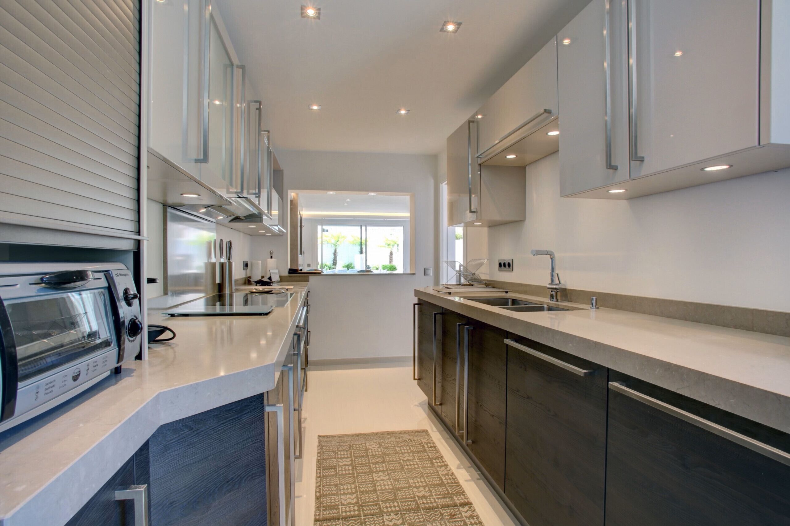 A modern kitchen with a built-in oven, a sink, and stainless steel cabinets.