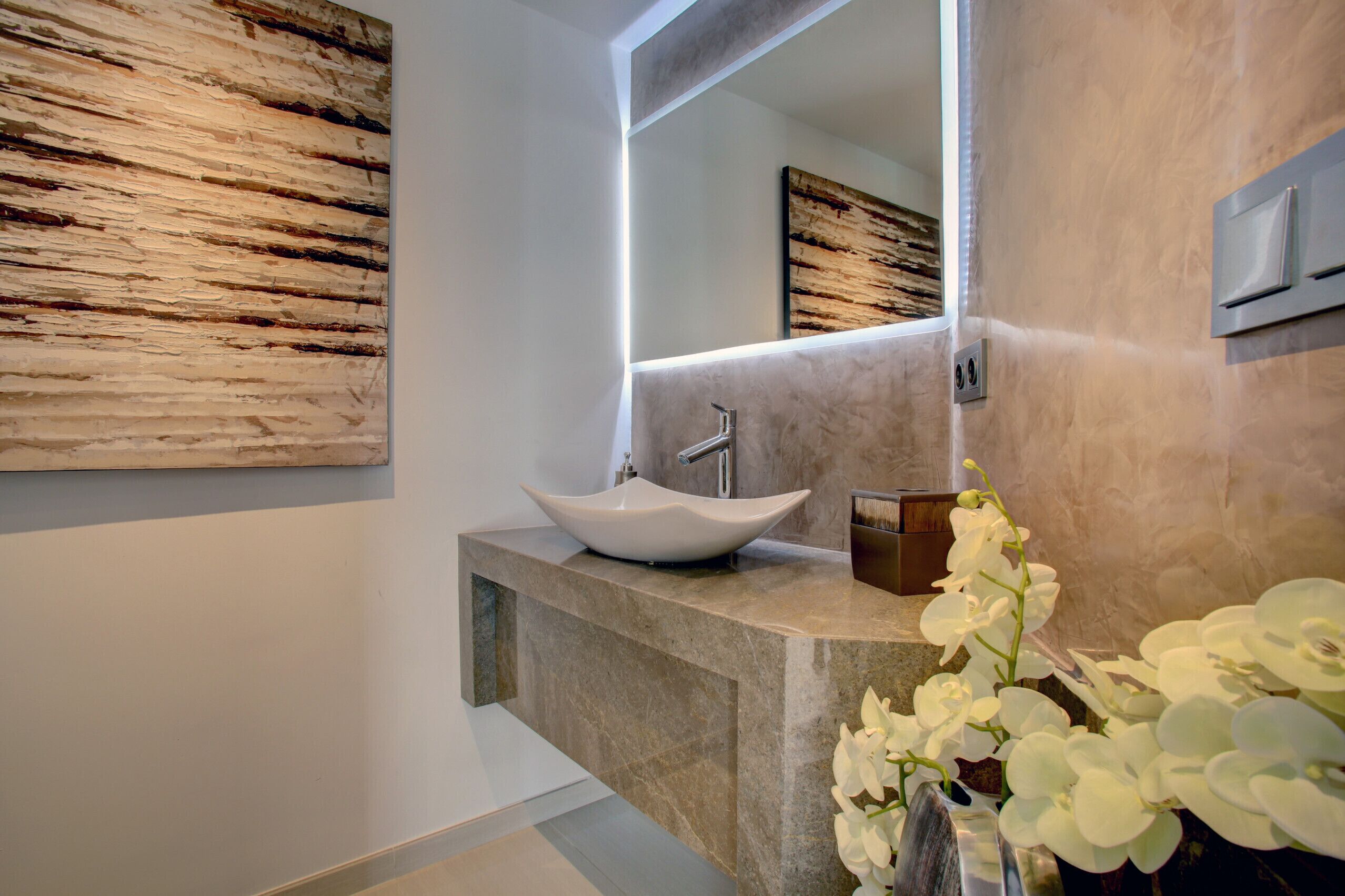 A modern bathroom with a large mirror, a vessel sink, and a marble countertop.