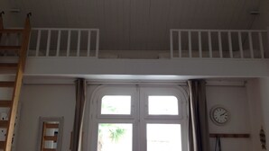 A room with a loft bed, a ladder, a window with curtains, a wall clock, and a small shelf with decorative items. - Charming Maisonette Pornic Gourmalon, near beaches, Thalasso, Shops (Pornic)