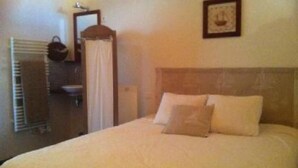 A hotel room with a bed, a bedside table, a mirror, a towel rack, and a framed picture on the wall. - Charming Maisonette Pornic Gourmalon, near beaches, Thalasso, Shops (Pornic)