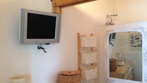 A bathroom with a mounted television, a mirror with a decorative frame, and a wooden shelf with a wicker basket. - Charming Maisonette Pornic Gourmalon, near beaches, Thalasso, Shops (Pornic)