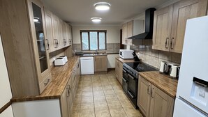 Una cocina moderna con armarios de madera, horno empotrado y microondas.