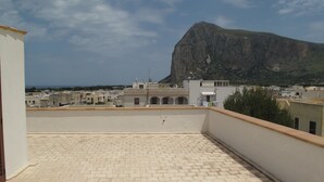 Una terraza en la azotea con vistas a una montaña y edificios a lo lejos.