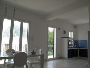 A spacious kitchen with a dining area, large windows, and a view of a mountain.