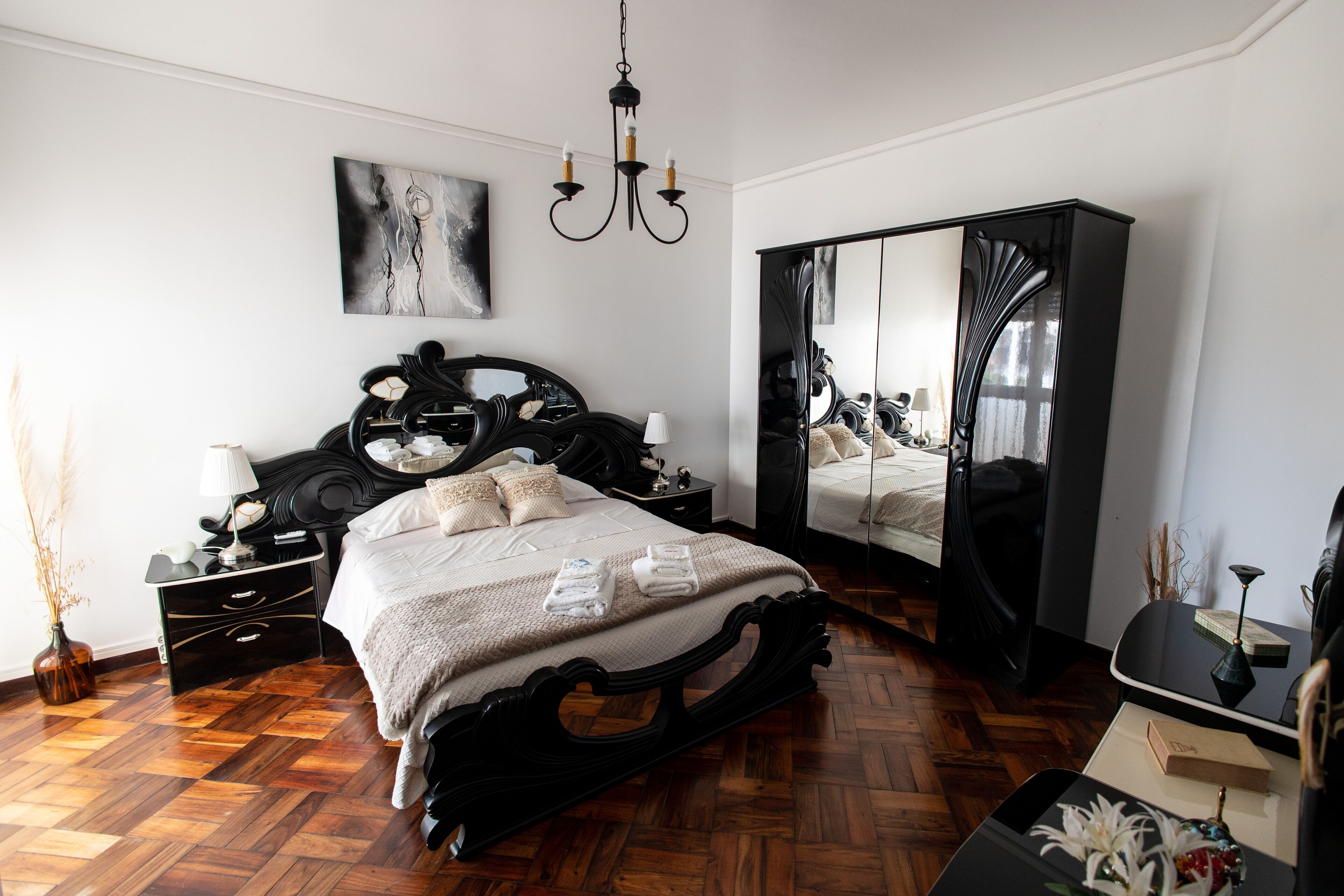 Une chambre à coucher avec un grand lit, une armoire, une table de chevet et un miroir.