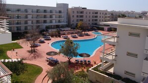 Ett hotell med en swimmingpool, flera balkonger och utsikt över det omgivande området.