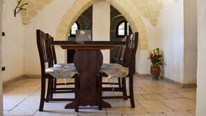 A dining area with a stone arch, a wooden table, and chairs. - "Trulli Monte Madre 2" with Private Swimming Pool (San Vito dei Normanni)