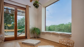 A room with a large window, a sliding glass door, a cushioned bench, a woven basket, and a potted plant. - SA PUNTA - Villa with private pool in Son Carrio. Free WiFi (Sant Llorenç des Cardassar)