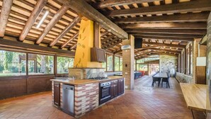 An open kitchen with a brick island, wooden beams, and large windows.