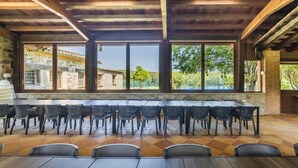A spacious room with a high ceiling, large windows, and a view of a stone building and greenery outside.