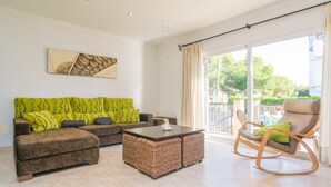 A living room with a brown sofa, a wicker coffee table, and a rocking chair. - LLUNA HOME - Chalet with terrace in Colonia de Sant Jordi. Free WiFi (Ses Salines)