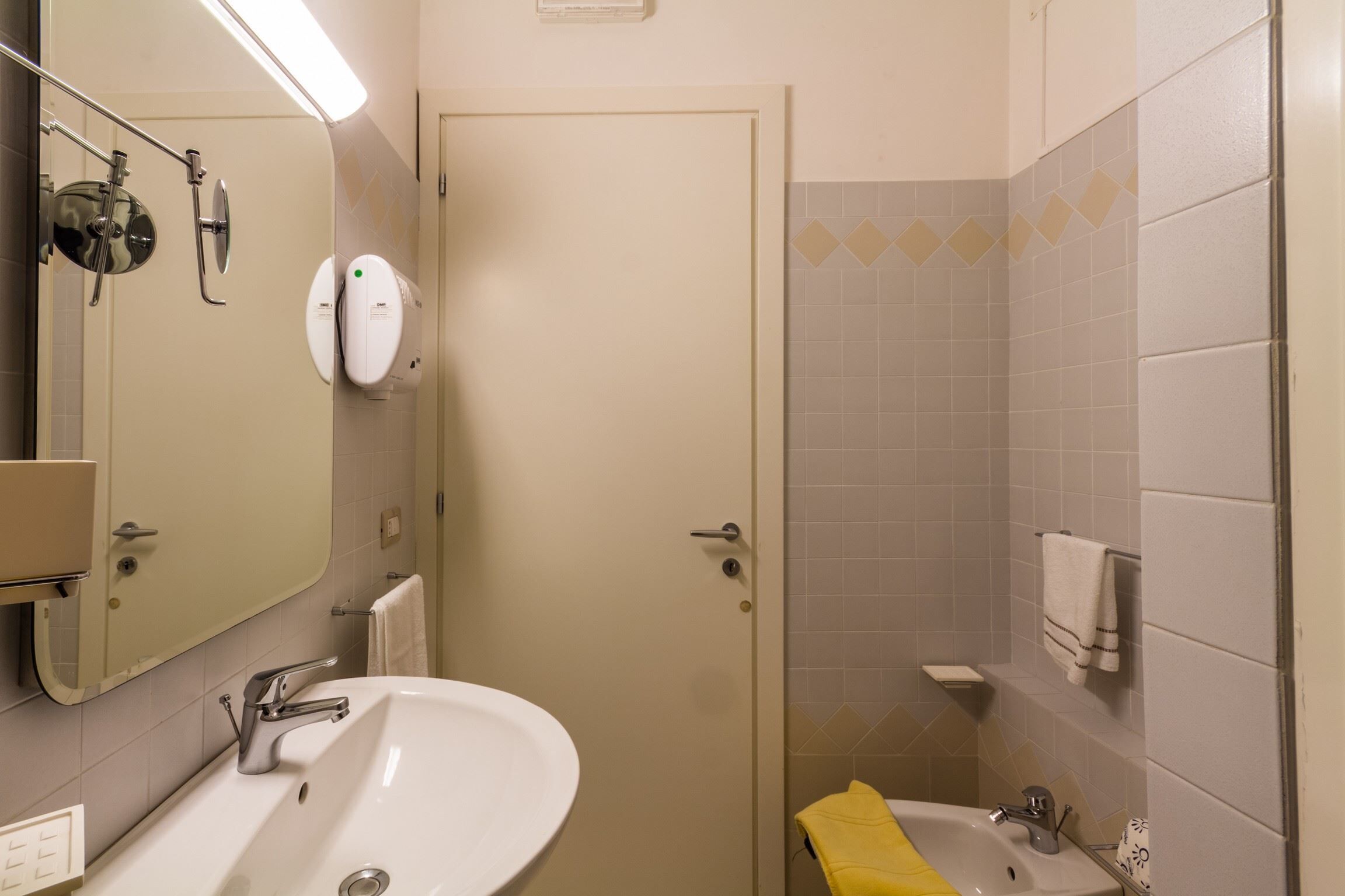 A bathroom with a sink, mirror, and shower.