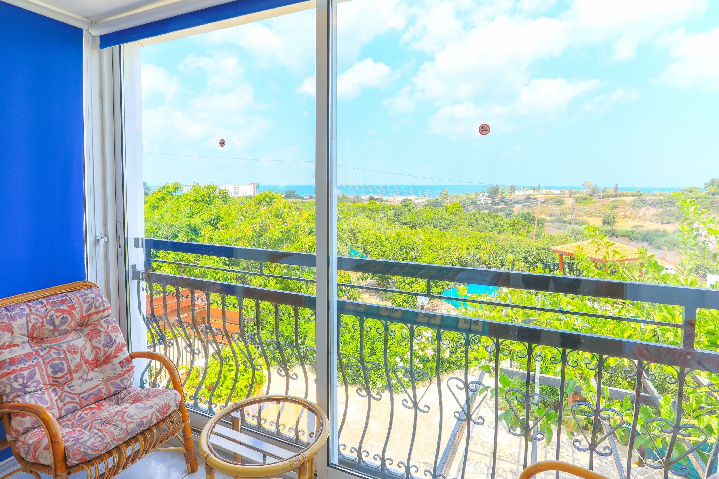 Un balcon donnant sur un paysage verdoyant et une étendue d’eau visible au loin.