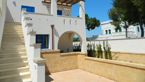 Un bâtiment blanc doté d’un escalier, d’une pergola et d’une arche.