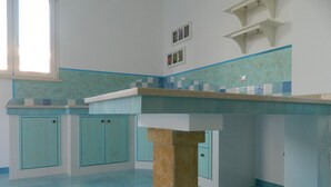 Une cuisine avec des carreaux bleus, une colonne centrale et des placards.