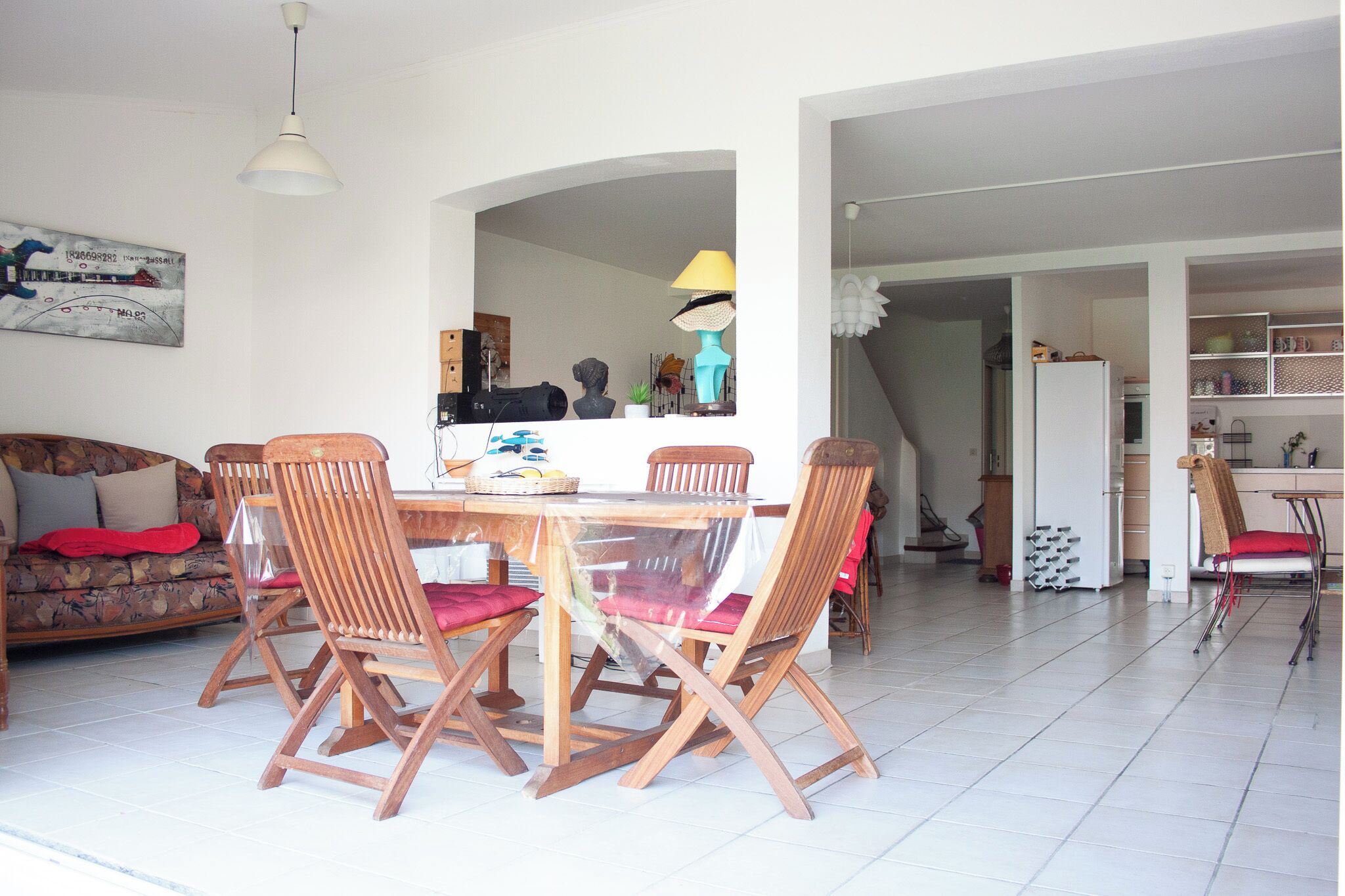 Un coin repas avec une table et des chaises en bois, un canapé et, au fond, une cuisine.