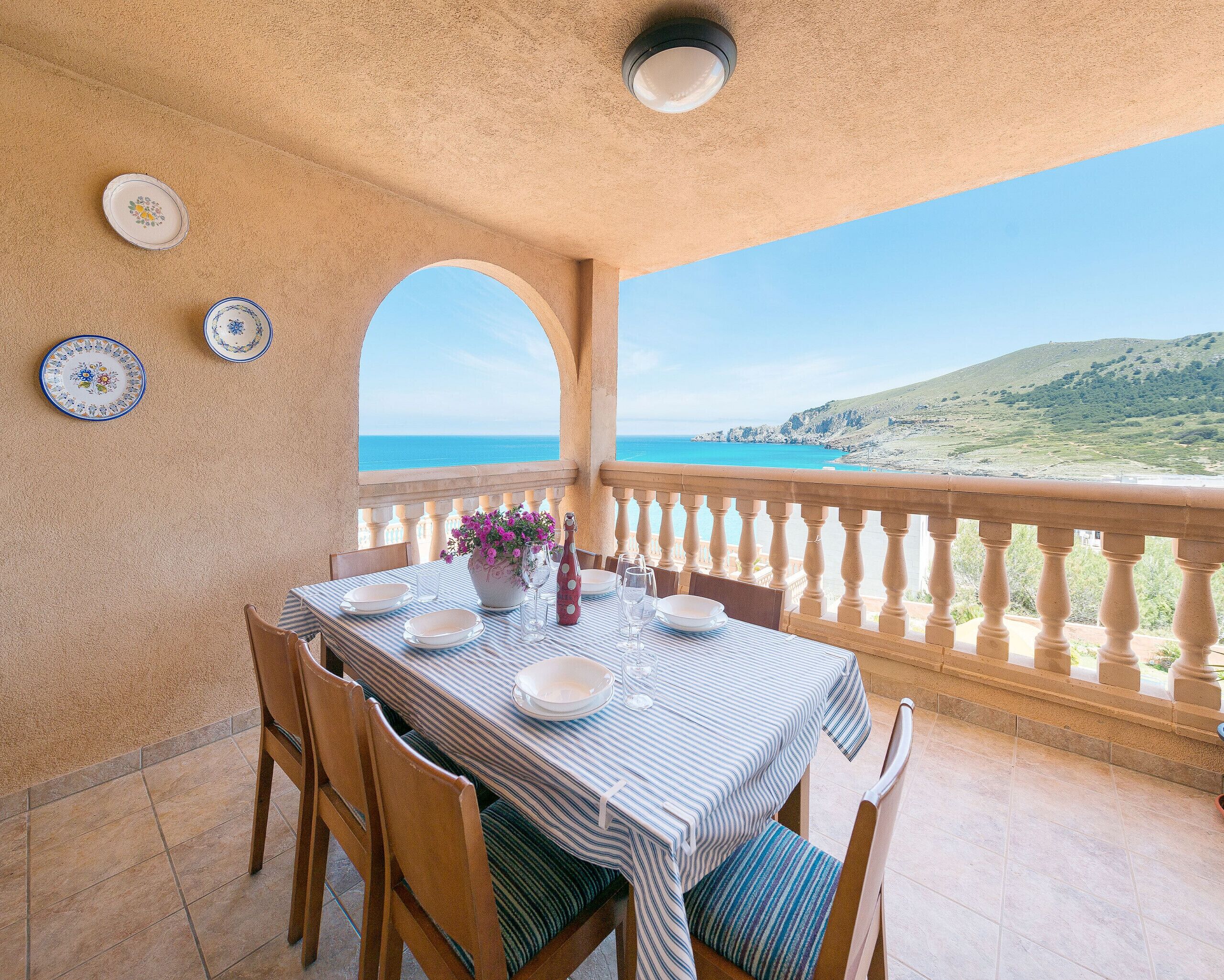 Un coin repas avec une table dressée pour deux personnes, offrant une vue sur la côte.