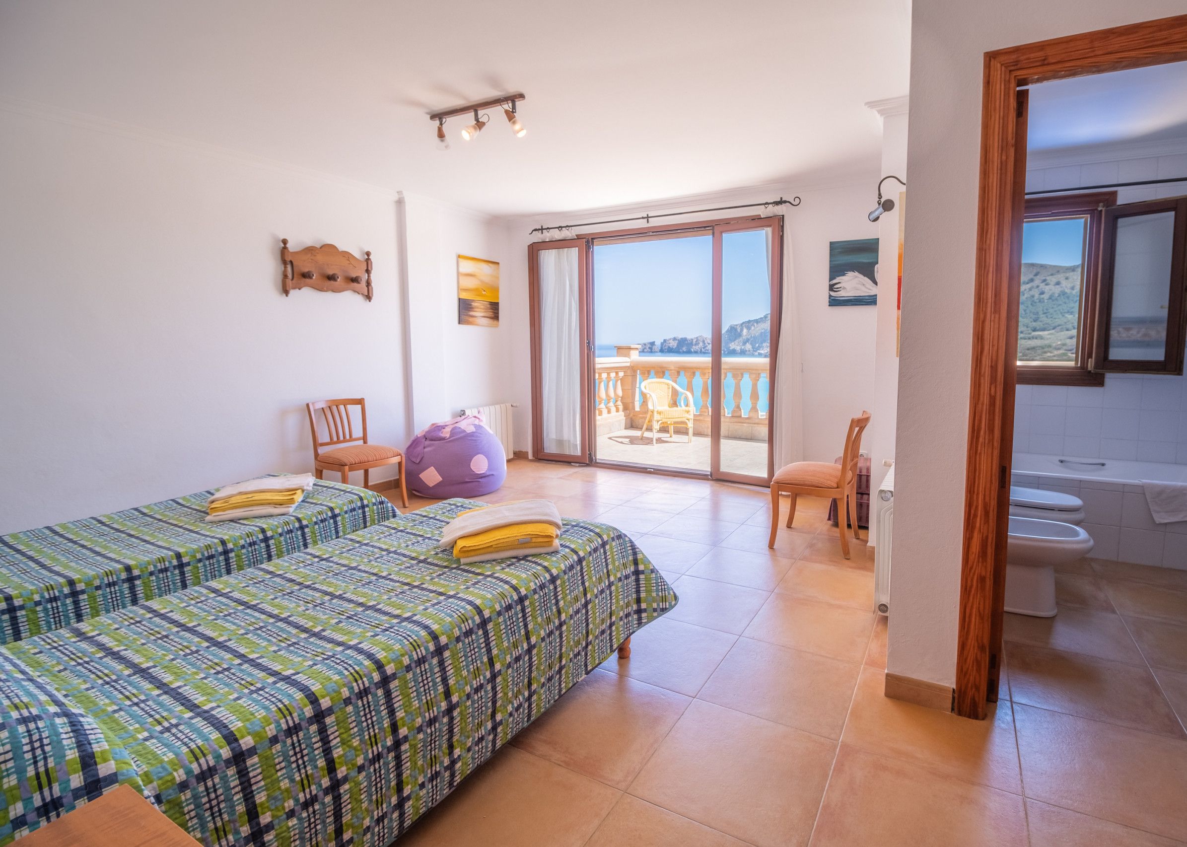 Un dormitorio con dos camas, un balcón, un baño y vistas al mar.