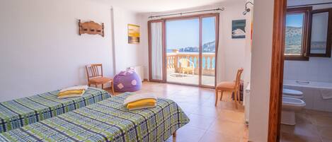 Un dormitorio con dos camas, un balcón, un baño y vistas al mar.