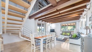Ein geräumiger Wohnbereich mit Esstisch, Stühlen, einer Couch und einer Treppe.