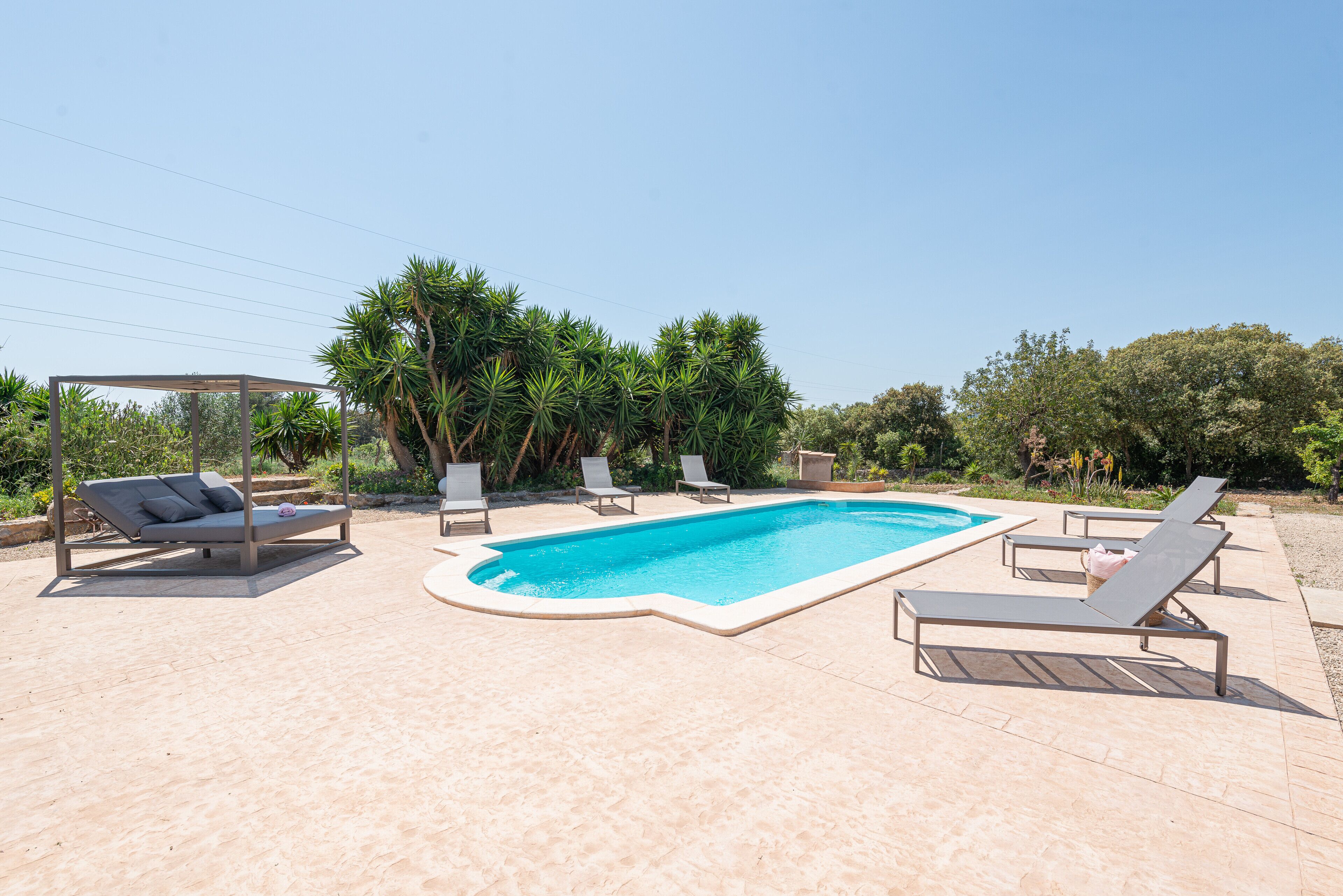 Une piscine avec des chaises longues et un espace de détente abrité.