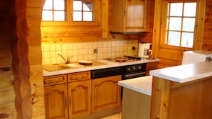 Una cocina estilo cabaña de madera con una isla central, armarios de madera y un salpicadero de azulejos.
