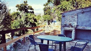 En udendørs patio med et bord og stole, omgivet af et træhegn og en stenvæg.