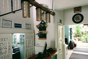 A reception area with a desk, computer, and hanging lanterns. There are signs on the wall, including one labeled "RECEPCIÓN." - Hotel Boutique Los Remansos (Palmira)