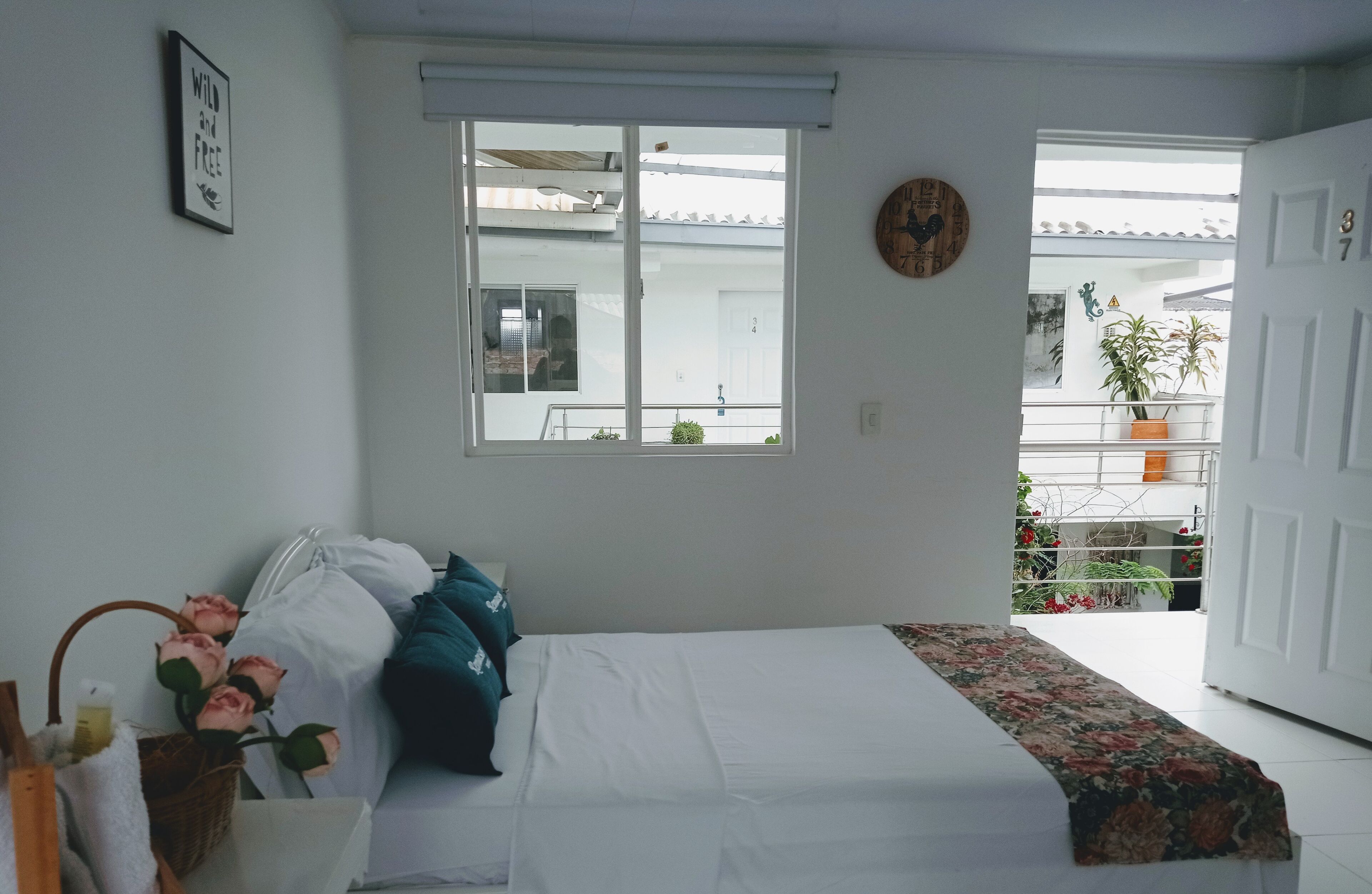 Un dormitorio con cama, ventana, puerta y balcón con plantas.