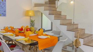 A dining area with a glass table, orange tablecloth, and a staircase with wooden steps. - Villa Jade II (Can Picafort)