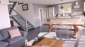 En moderne stue med en grå sofa, et træbord og en trappe til en overetage.