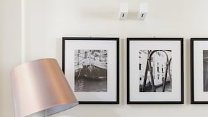 A living room with a dark sofa, a lamp, and three framed black and white photographs on the wall.