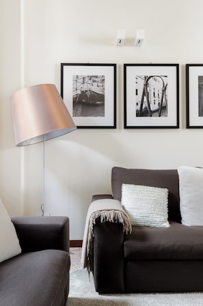 A living room with a dark sofa, a lamp, and three framed black and white photographs on the wall. - Ca' Moro - Salina (Venice)